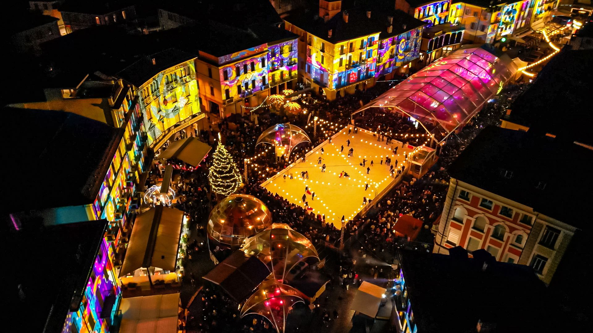 Illuminated ice slide with stalls in the background.